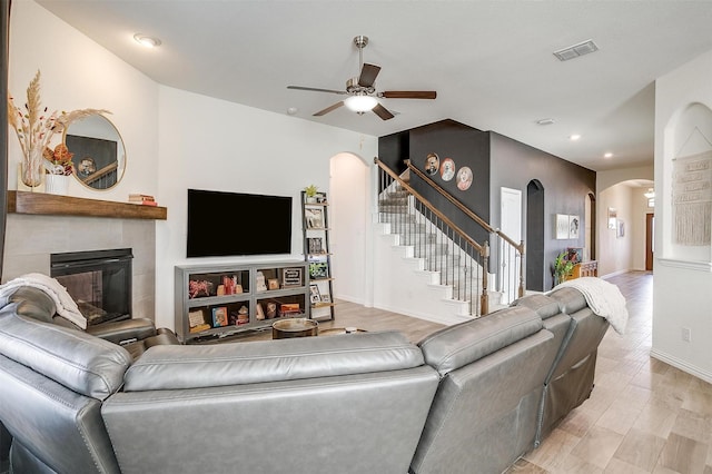 living room featuring ceiling fan, light hardwood / wood-style floors, and a tile fireplace