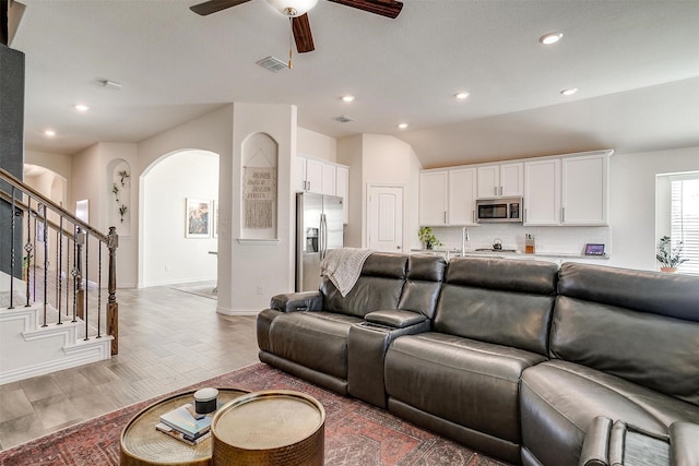 living room with vaulted ceiling, ceiling fan, and light hardwood / wood-style flooring