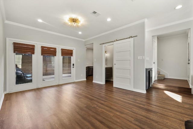 unfurnished living room featuring crown molding, a barn door, and dark wood-type flooring