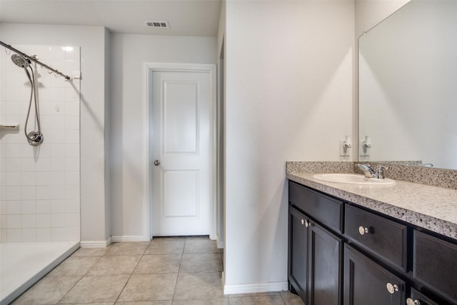 bathroom with vanity, a tile shower, and tile patterned floors