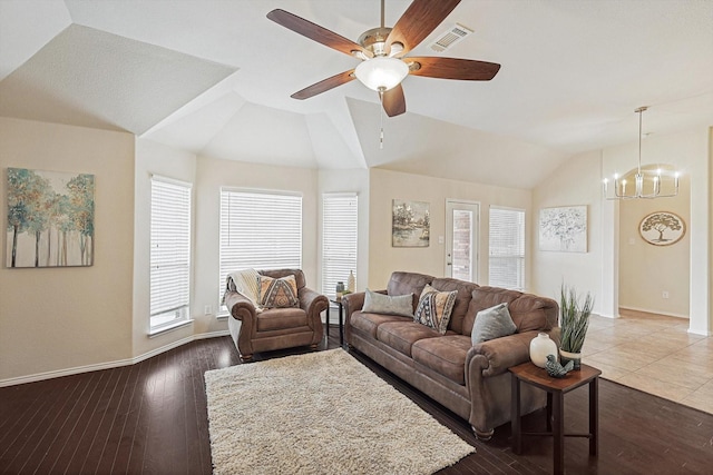 living room with dark wood-type flooring, lofted ceiling, a wealth of natural light, and ceiling fan with notable chandelier