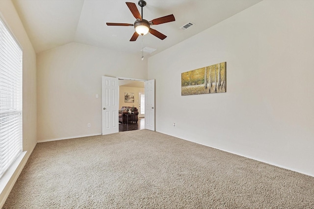 empty room featuring ceiling fan, lofted ceiling, carpet flooring, and a wealth of natural light