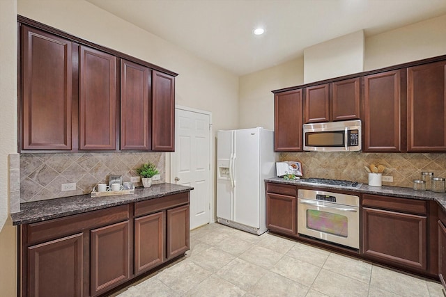 kitchen featuring stainless steel appliances, dark stone counters, and backsplash