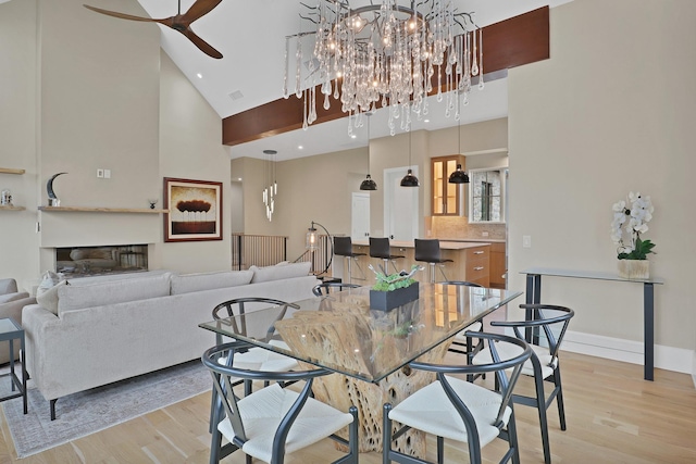 dining space featuring ceiling fan, light wood-type flooring, and high vaulted ceiling