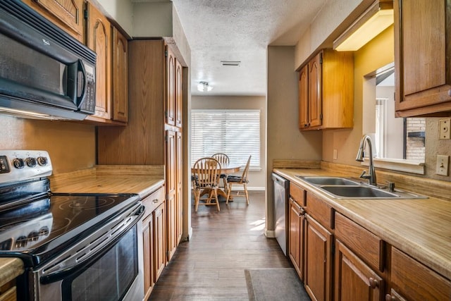 kitchen with appliances with stainless steel finishes, dark hardwood / wood-style floors, sink, and a textured ceiling