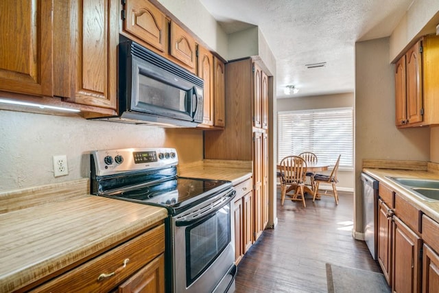 kitchen with appliances with stainless steel finishes, dark hardwood / wood-style floors, sink, and a textured ceiling