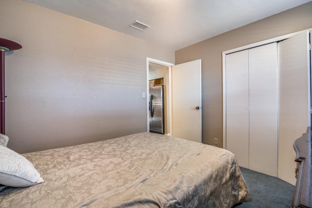 carpeted bedroom featuring stainless steel refrigerator and a closet