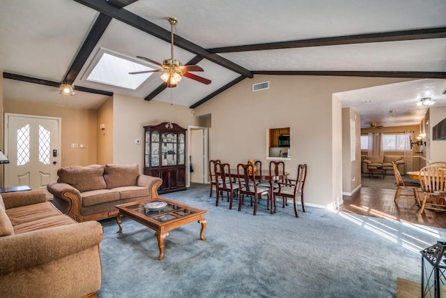 living room featuring dark carpet, a wealth of natural light, lofted ceiling with skylight, and ceiling fan