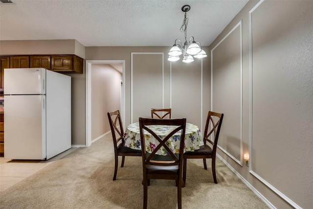 carpeted dining room with an inviting chandelier and a textured ceiling