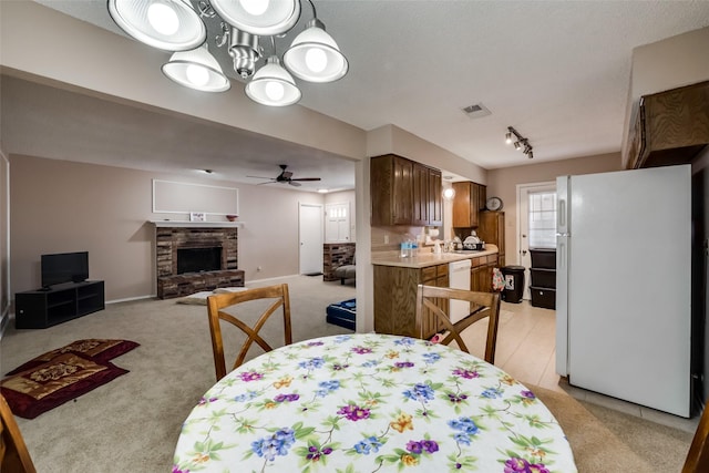 carpeted dining area featuring ceiling fan, a fireplace, and sink