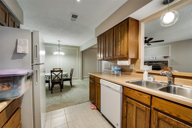 kitchen with sink, light carpet, a textured ceiling, pendant lighting, and white appliances