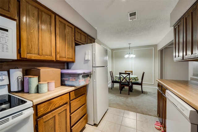 kitchen with an inviting chandelier, light carpet, hanging light fixtures, a textured ceiling, and white appliances