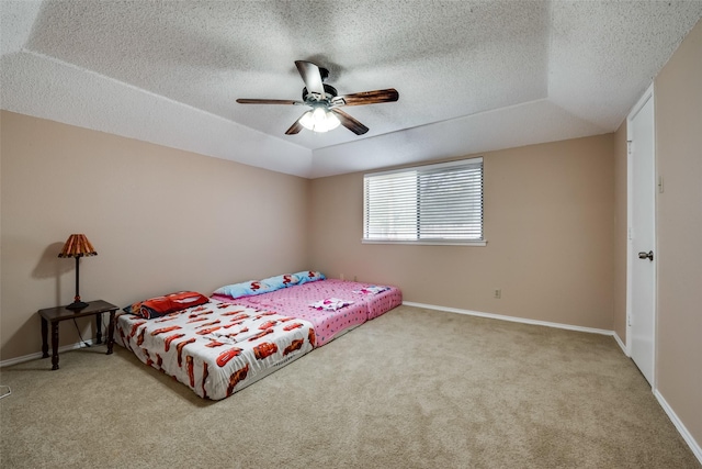 bedroom with ceiling fan, a tray ceiling, and light colored carpet