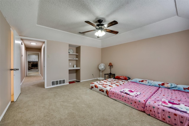 carpeted bedroom featuring a textured ceiling, ceiling fan, and a tray ceiling