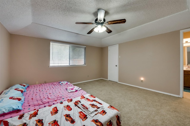 carpeted bedroom featuring ceiling fan, ensuite bathroom, a raised ceiling, and a textured ceiling