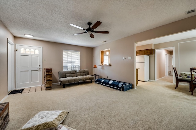 living room with ceiling fan, light colored carpet, and a textured ceiling