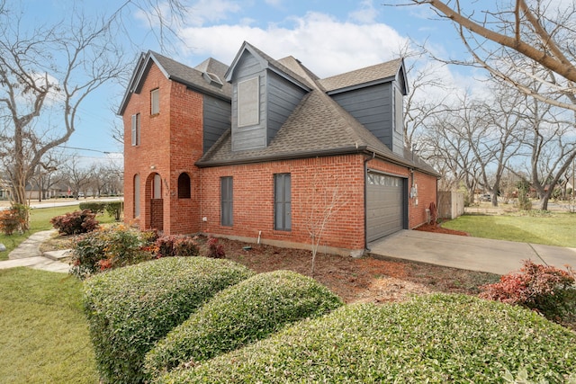 view of side of property featuring driveway, roof with shingles, a yard, a garage, and brick siding