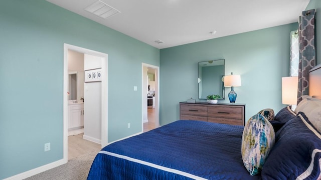 bedroom featuring light colored carpet and ensuite bathroom