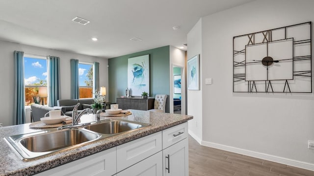 kitchen with hardwood / wood-style flooring, white cabinetry, and sink