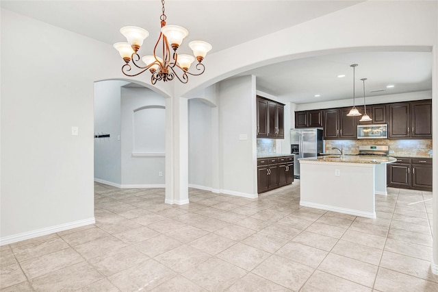 kitchen featuring pendant lighting, appliances with stainless steel finishes, backsplash, dark brown cabinets, and a center island with sink