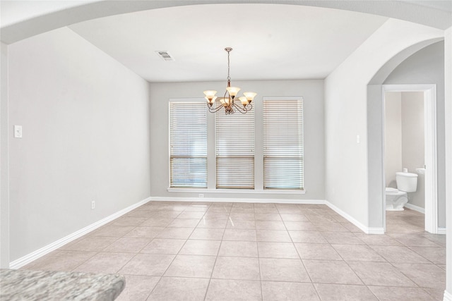 tiled spare room with a notable chandelier