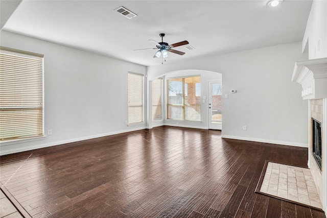 unfurnished living room with dark hardwood / wood-style flooring, a tile fireplace, and ceiling fan