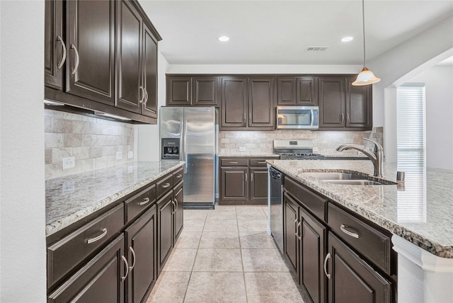 kitchen featuring dark brown cabinetry, sink, decorative light fixtures, and appliances with stainless steel finishes