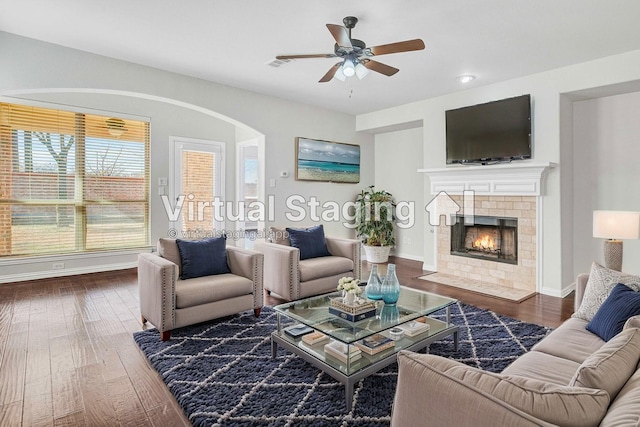 living room with ceiling fan, dark hardwood / wood-style floors, and a tile fireplace