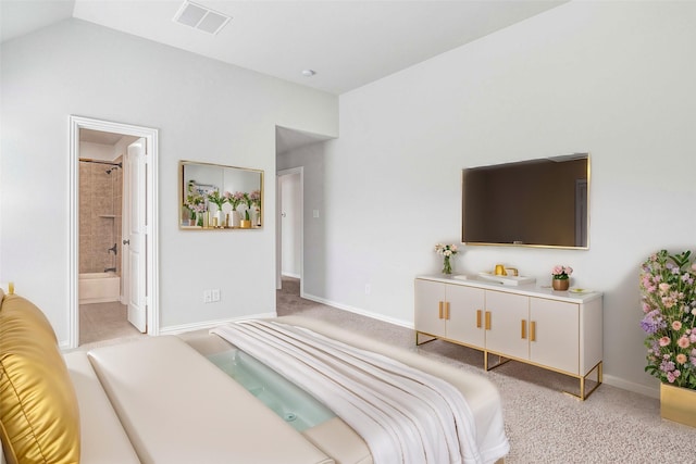 bedroom featuring lofted ceiling, light colored carpet, and ensuite bath