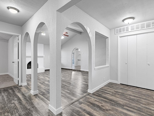 foyer entrance featuring dark hardwood / wood-style floors, ceiling fan, a fireplace, and a textured ceiling