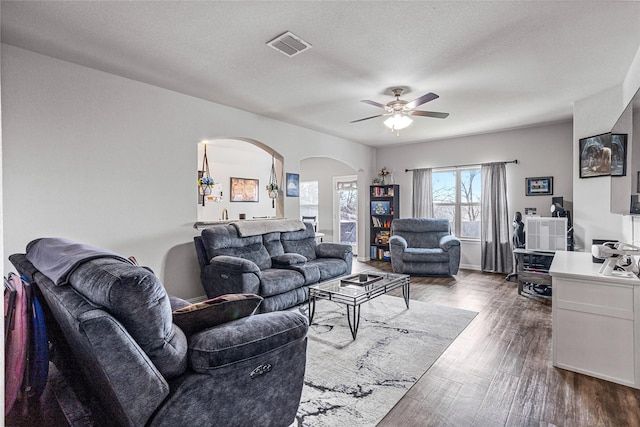 living room featuring dark hardwood / wood-style flooring, ceiling fan, and a textured ceiling