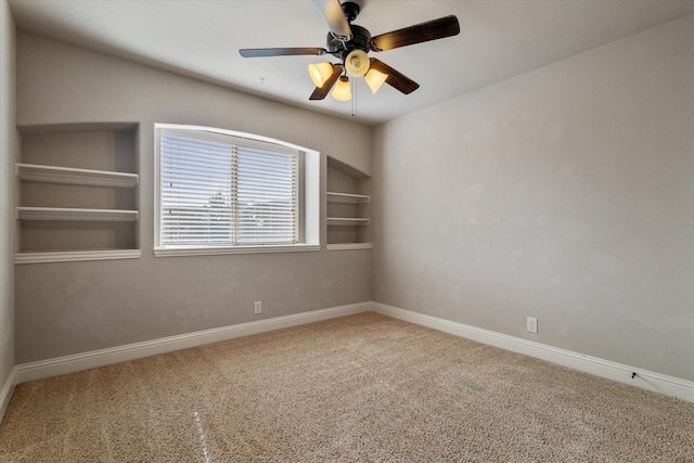 carpeted spare room with built in features and ceiling fan