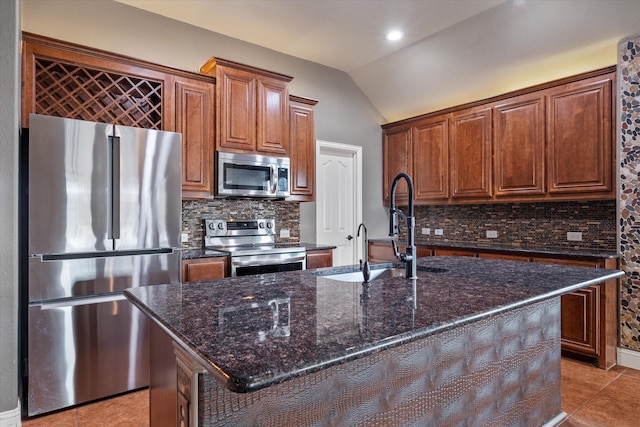 kitchen featuring appliances with stainless steel finishes, tasteful backsplash, an island with sink, lofted ceiling, and sink