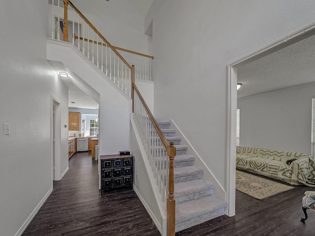 stairs with hardwood / wood-style flooring, a textured ceiling, and a high ceiling