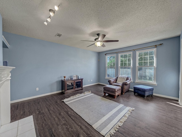 sitting room featuring dark wood-type flooring, ceiling fan, a fireplace, and a textured ceiling