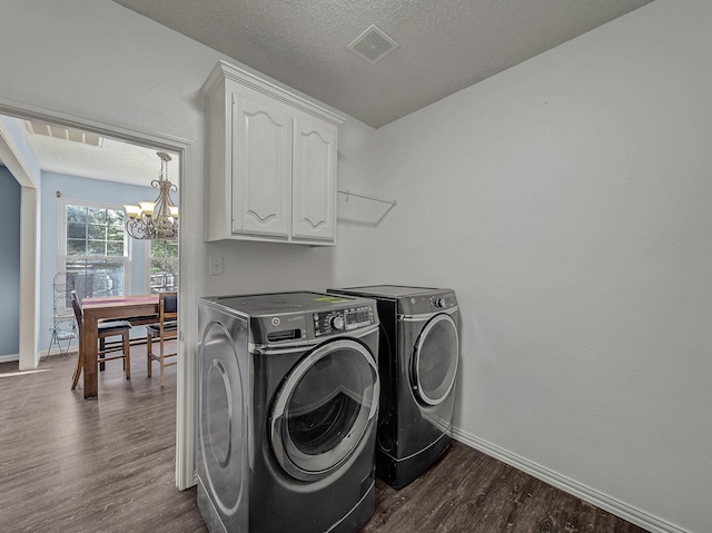 clothes washing area featuring washer and dryer, dark hardwood / wood-style flooring, cabinets, a notable chandelier, and a textured ceiling