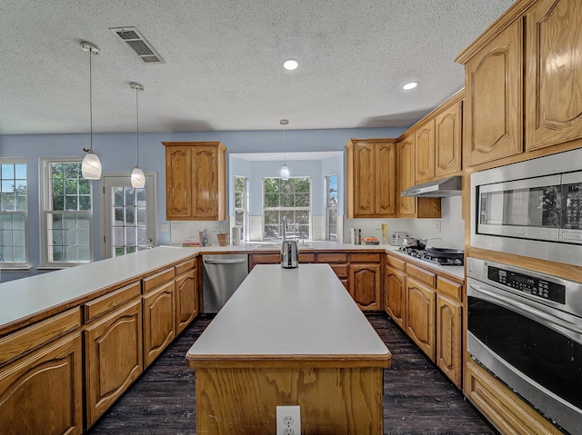 kitchen featuring stainless steel appliances, a center island, pendant lighting, and dark wood-type flooring