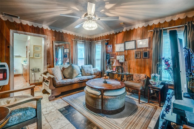 living area featuring ceiling fan and wooden walls