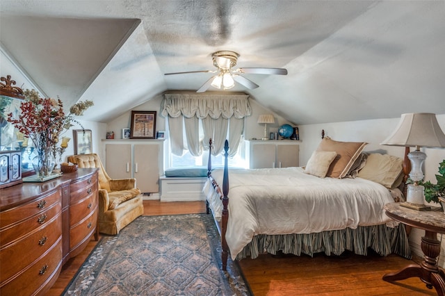 bedroom with ceiling fan, lofted ceiling, dark hardwood / wood-style flooring, and a textured ceiling