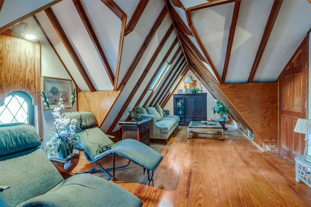 living area featuring lofted ceiling with beams, light wood-type flooring, and wood walls