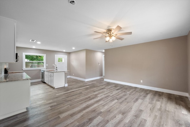 kitchen featuring sink, light hardwood / wood-style flooring, light stone countertops, white cabinets, and stainless steel dishwasher