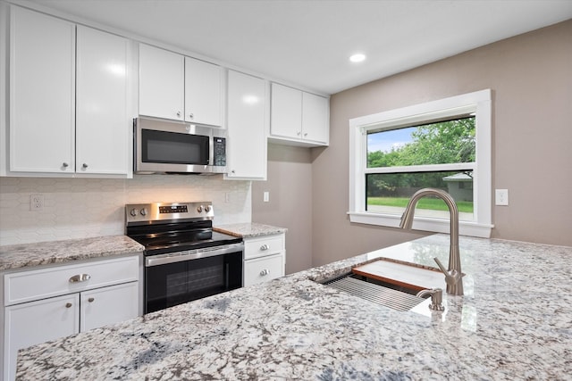 kitchen with white cabinetry, sink, light stone counters, and appliances with stainless steel finishes