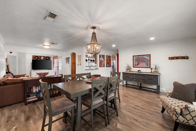 dining space featuring crown molding, hardwood / wood-style floors, and a notable chandelier