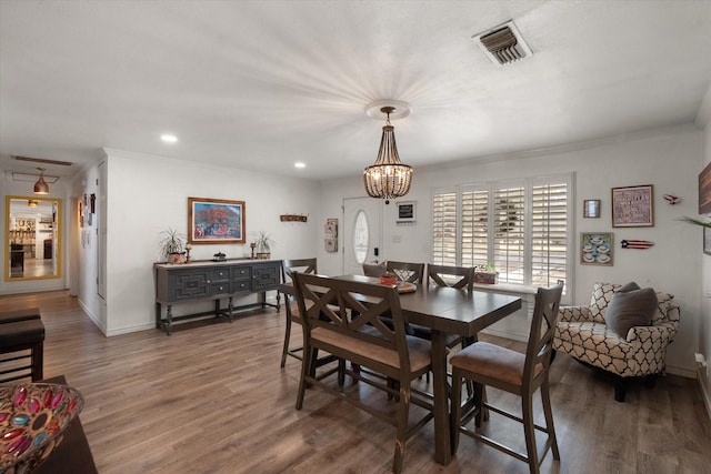 dining area with crown molding, dark wood-type flooring, and a chandelier