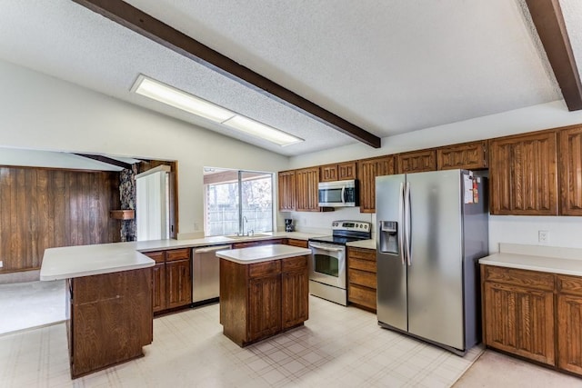 kitchen with vaulted ceiling, a kitchen island, sink, and appliances with stainless steel finishes