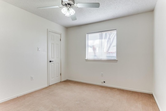 unfurnished room featuring ceiling fan, light carpet, and a textured ceiling