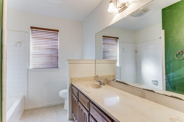 full bathroom with tiled shower / bath, vanity, and toilet