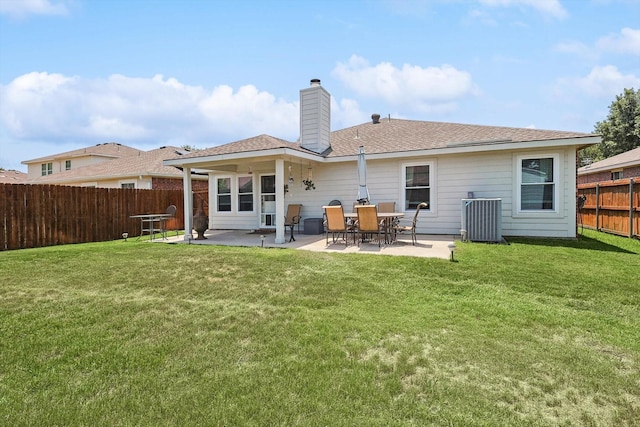 rear view of property featuring a lawn, cooling unit, and a patio area