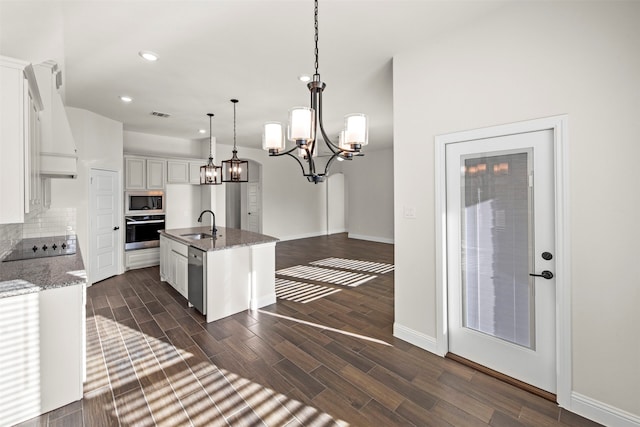 kitchen with premium range hood, a kitchen island with sink, white cabinetry, appliances with stainless steel finishes, and decorative light fixtures