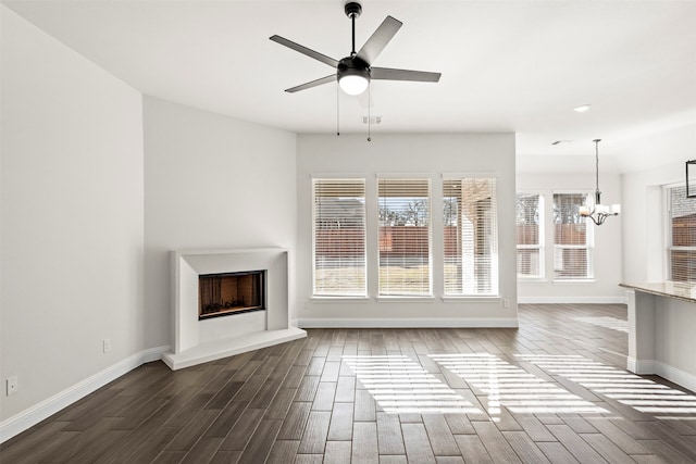 unfurnished living room with ceiling fan with notable chandelier